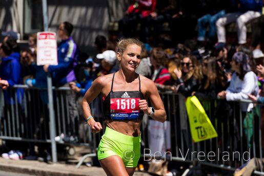 A female runner smiling in the final mile of the 126th Boston Marathon
