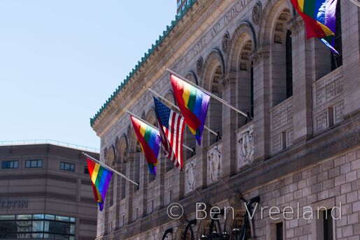 An American flag flanked by pride flags on the façade of the Boston Public Library