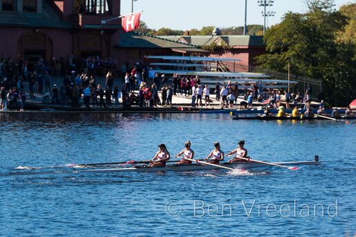 Saint Joseph's University women's rowing team passes Harvard's Newell boathouse during the Head of the Charles Regatta