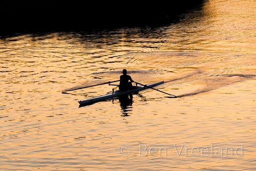 A single rower reflected in an orange Charles River at sunset