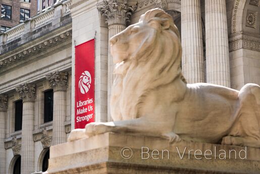 Red 'Libraries Make Us Stronger' banner on the New York Public Library, with 'Fortitude' the stone lion in the foreground