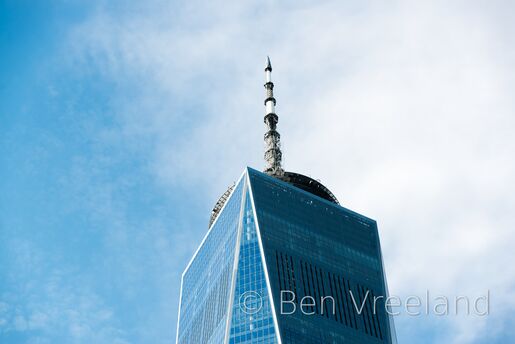 Spire of New York City's One World Trade Center as seen from the ground on a sunny day